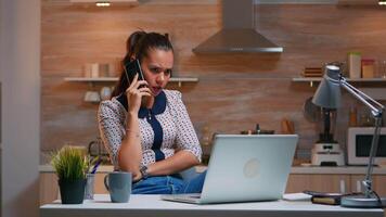 Fernbedienung Mitarbeiter Sprechen beim Telefon während Arbeiten beim Laptop spät beim Nacht. beschäftigt konzentriert Freiberufler mit modern Technologie Netzwerk kabellos tun im Laufe der Zeit zum Job lesen Schreiben, suchen nehmen brechen video