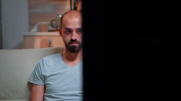 fokuserade man bläddring på internet information för deadline projekt använder sig av bärbar dator dator medan Sammanträde på soffa i levande rum. frilansare avkopplande på soffa tittar på prata visa sent på natt video