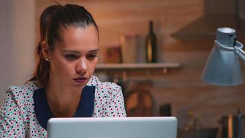 cansado o negócio mulher lendo relatórios sentado dentro frente do computador portátil atrasado às noite trabalhando a partir de lar. ocupado focado empregado usando moderno tecnologia rede sem fio fazendo hora extra escrita, procurando. video