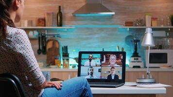 mujer de negocios en conferencia trabajando remotamente desde hogar sentado en el cocina tarde a noche. dama utilizando moderno tecnología red inalámbrico hablando en virtual reunión a medianoche haciendo tiempo extraordinario video