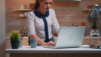 Freiberufler Empfangen gut Nachrichten auf Laptop Arbeiten von Zuhause Sitzung im das Küche. begeistert konzentriert Mitarbeiter mit modern Technologie Netzwerk kabellos tun im Laufe der Zeit studieren Schreiben, suchen video