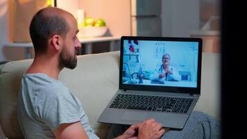 Caucasian male chatting with physician doctor during online telemedicine consultation sitting in home kitchen. Sick man disscusing about illness symptoms and headlcare treatment video