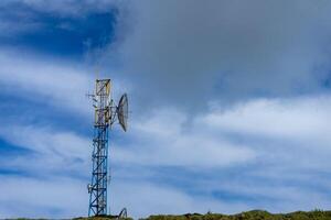 Modern telecom tower stands tall against dramatic mountain backdrop in Serra do Cume, Terceira Island, Azores. A symbol of connectivity in remote beauty. photo