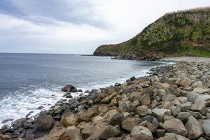 Rocky coastline of Terceira Island, Azores. Dramatic cliffs meet the Atlantic Ocean in this stunning beach scene. Perfect for nature lovers and travel enthusiasts. photo