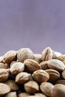 Pile of almonds in shells against a purple background. Vibrant composition capturing natural textures and colors. photo