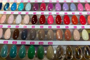 A display of painted nail samples in a store, featuring various colors and designs. The samples are neatly arranged, showcasing a diverse range of nail polishes, from bright hues to subtle shades. photo