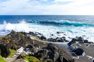 Powerful waves crash along the shoreline of Cinco Ribeiras, a scenic bathing area on Terceira Island, Azores. photo