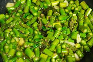 Fresh green asparagus diced and sizzling in a skillet on the stove. photo