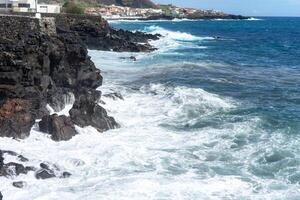 Idyllic scene of clear blue sea crashing against volcanic black rocks along the cliffs of Terceira Island, Azores. photo