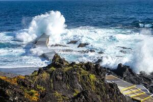 Powerful waves crash along the shoreline of Cinco Ribeiras, a scenic bathing area on Terceira Island, Azores. photo