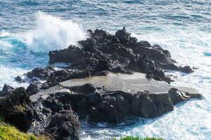 Powerful waves crash along the shoreline of Cinco Ribeiras, a scenic bathing area on Terceira Island, Azores. photo