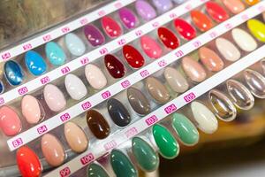 A display of painted nail samples in a store, featuring various colors and designs. The samples are neatly arranged, showcasing a diverse range of nail polishes, from bright hues to subtle shades. photo