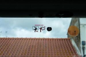Emergency exit signage and mandatory seatbelt use sticker on bus window. photo