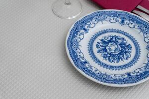 A white plate with blue patterns sits on a table in a traditional restaurant. The intricate design on the plate adds a touch of elegance to the simple yet inviting dining setting. photo