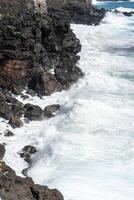 Idyllic scene of clear blue sea crashing against volcanic black rocks along the cliffs of Terceira Island, Azores. photo