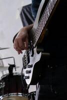 un hombre jugando un bajo guitarra en un casual ajuste. él es enfocado en su instrumento, dedos deslizamiento terminado el instrumentos de cuerda. su relajado postura y casual atuendo sugerir un relajado música sesión. foto