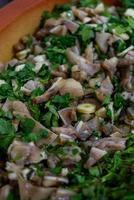 Close-up of traditional Portuguese dish Orelha de Porco de Coentrada. The image showcases tender pork ear slices, garnished with fresh cilantro and garlic photo