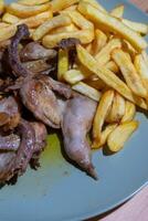 Fried quails with French fries on a white plate, a classic Portuguese dish. The quails are golden-brown and crispy, complemented by a generous serving of golden French fries for a hearty meal. photo