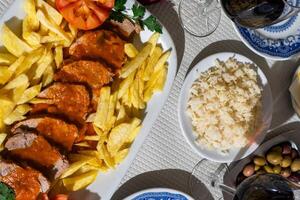 un plato de ternera estofado en un Rico tomate salsa, servido con crujiente papas fritas, es presentado en un mesa a un tradicional alentejo restaurante. el rústico ajuste y abundante plato crear un atractivo atmósfera. foto