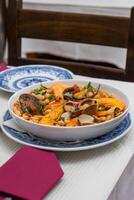 A traditional Alentejo restaurant serves a vibrant seafood feijoada. This dish features prawns, shellfish, and beans in a rustic clay pot, offering a hearty and authentic Portuguese experience. photo