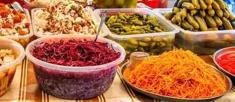 un puesto con en escabeche vegetales a un bazar encimera. en escabeche remolachas, pepinos, Chucrut, estilo coreano zanahorias y pepinos foto