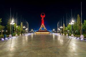 UZBEKISTAN, TASHKENT - SEPTEMBER 15, 2023 Illuminated monument of independence in the form of a stele with a Humo bird in the New Uzbekistan park at nighttime in autumn. photo