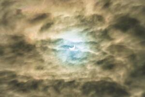 Partial solar eclipse passing behind the clouds. photo