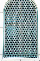 The window of a Muslim mosque behind bars in the form of a geometric hexagonal Islamic ornament. photo