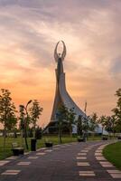 UZBEKISTAN, TASHKENT - SEPTEMBER 15, 2023 Monument of Independence in the form of a stele with a Humo bird on a twilight with dramatic cliods in the New Uzbekistan park. photo