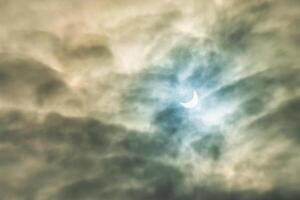 Partial solar eclipse passing behind the clouds. photo