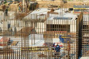 RUSSIA, KALUGA - AUGUST 15, 2022 Workers assembling the frame of a building from rebar. photo