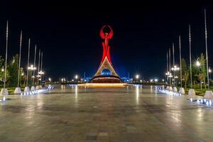 UZBEKISTAN, TASHKENT - SEPTEMBER 15, 2023 Illuminated monument of independence in the form of a stele with a Humo bird in the New Uzbekistan park at nighttime in autumn. photo