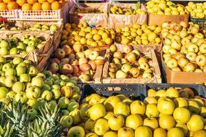 Tashkent, Uzbekistan - January 30,2022 Fruit stall in the market, illuminated by the sun. Oranges, pineapples, lemons and apples. photo