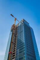 A crane building a skyscraper against a blue sky. photo