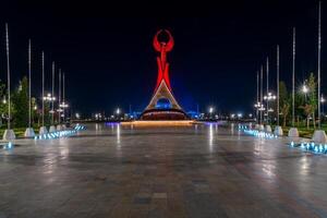 UZBEKISTAN, TASHKENT - SEPTEMBER 15, 2023 Illuminated monument of independence in the form of a stele with a Humo bird in the New Uzbekistan park at nighttime in autumn. photo