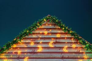 Christmas balls, toys and glowing garlands on an artificial spruce branch and wooden background. photo