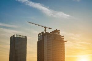A crane building a skyscraper against a sunset. photo