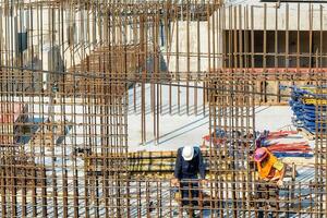 RUSSIA, KALUGA - AUGUST 15, 2022 Workers assembling the frame of a building from rebar. photo