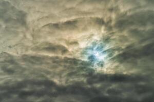 Partial solar eclipse passing behind the clouds. photo