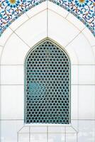 The window of a Muslim mosque behind bars in the form of a geometric hexagonal Islamic ornament. photo