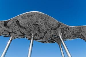 Street decorative decorations in the form of steel shiny abstract sculptures against a blue sky background. photo