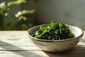 A plate with green salad made from chukka seaweed on a wooden table, illuminated by bright sunlight. Vegan seafood. photo