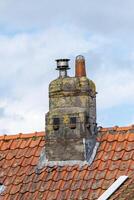 chimney on a roof with clay tiles photo