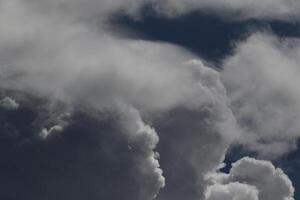 Cloudscape scenery, overcast weather above dark blue sky. Storm clouds floating in a rainy dull day with natural light. White and grey scenic environment background. Nature view. photo