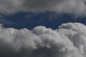 Cloudscape scenery, overcast weather above dark blue sky. Storm clouds floating in a rainy dull day with natural light. White and grey scenic environment background. Nature view. photo