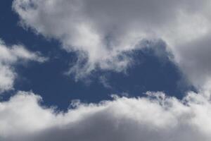 Cloudscape scenery, overcast weather above dark blue sky. Storm clouds floating in a rainy dull day with natural light. White and grey scenic environment background. Nature view. photo