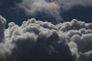 Cloudscape scenery, overcast weather above dark blue sky. Storm clouds floating in a rainy dull day with natural light. White and grey scenic environment background. Nature view. photo