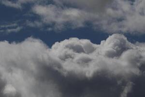 Cloudscape scenery, overcast weather above dark blue sky. Storm clouds floating in a rainy dull day with natural light. White and grey scenic environment background. Nature view. photo