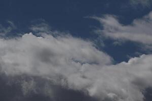 Cloudscape scenery, overcast weather above dark blue sky. Storm clouds floating in a rainy dull day with natural light. White and grey scenic environment background. Nature view. photo