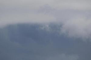 Cloudscape scenery, overcast weather above dark blue sky. Storm clouds floating in a rainy dull day with natural light. White and grey scenic environment background. Nature view. photo